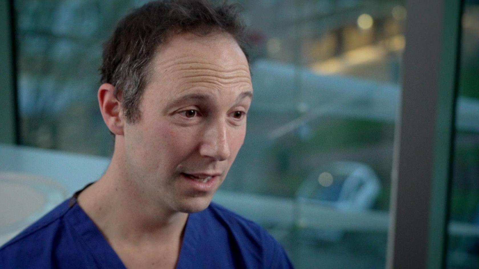 Mr Harry Petrushkin, who treated Nicki, is dressed in surgical scrubs and looks to the side of the camera