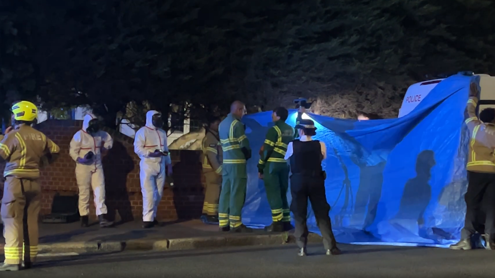 Picture of the scene on Hayes Lane showing fire, ambulance and police personnel including some holing up a blue covering