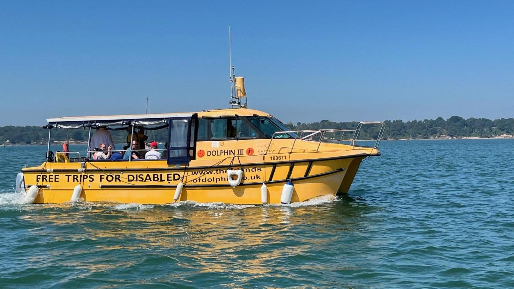 Another shot of Dolphin III, a clear harbour behind it with passengers onboard sitting under the cover that extends from the cockpit.