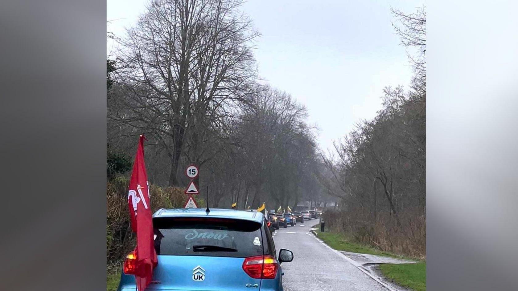 A set of cars carrying Lithuanian flags driving around Peterborough