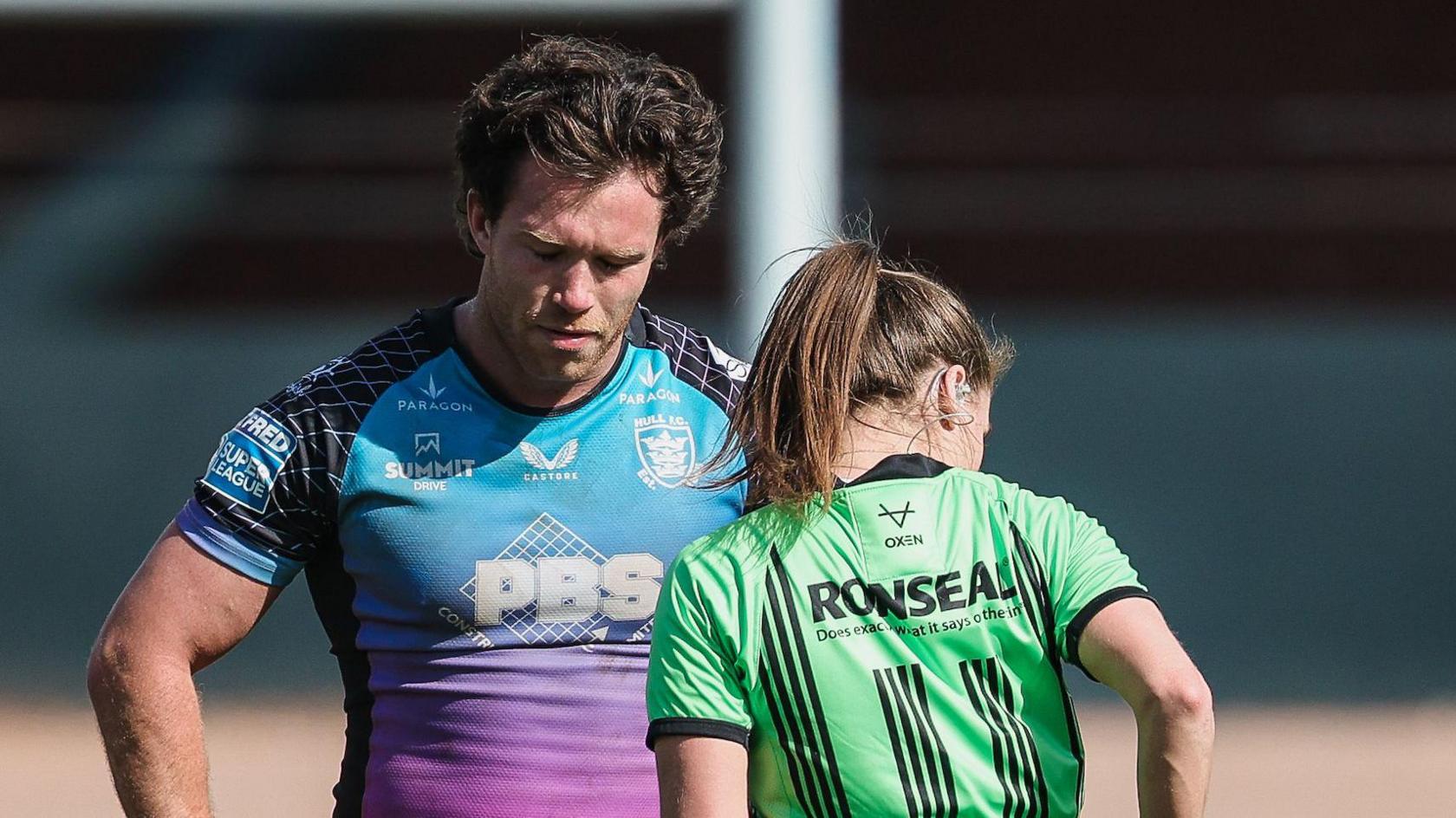 Hull FC forward Yusuf Aydin waiting with his eyes shut and head bowed as referee Tara Jones (with her back turned) is about to produce a red card from her back pocket 