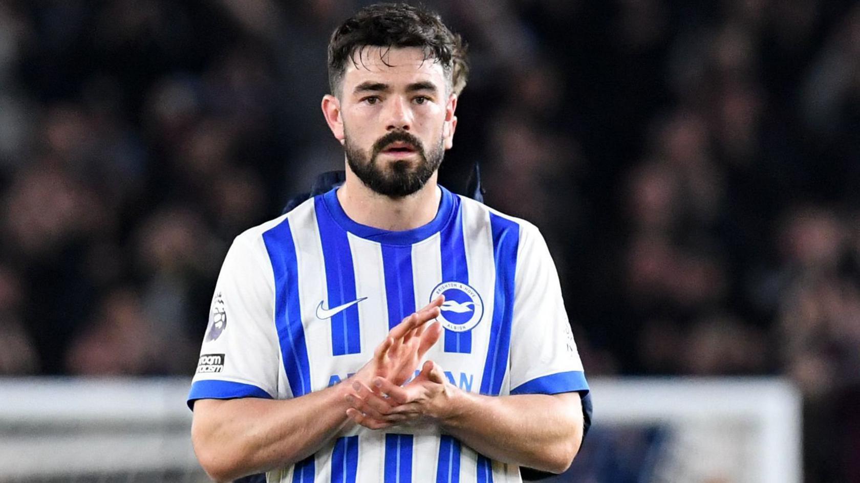 Eiran Cashin applauds Brighton fans following his debut against Aston Villa