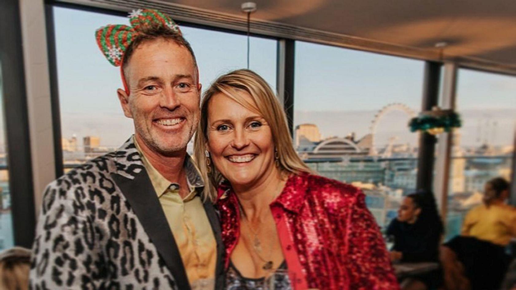 A middle-aged man and woman in fancy dress in London. They are smiling and look happy.