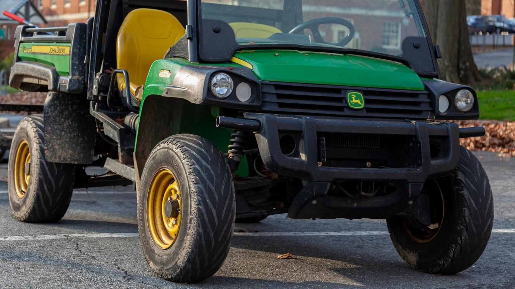 A green John Deere XUV 855D S4 crossover utility vehicle is parked in front of a building. - stock photo