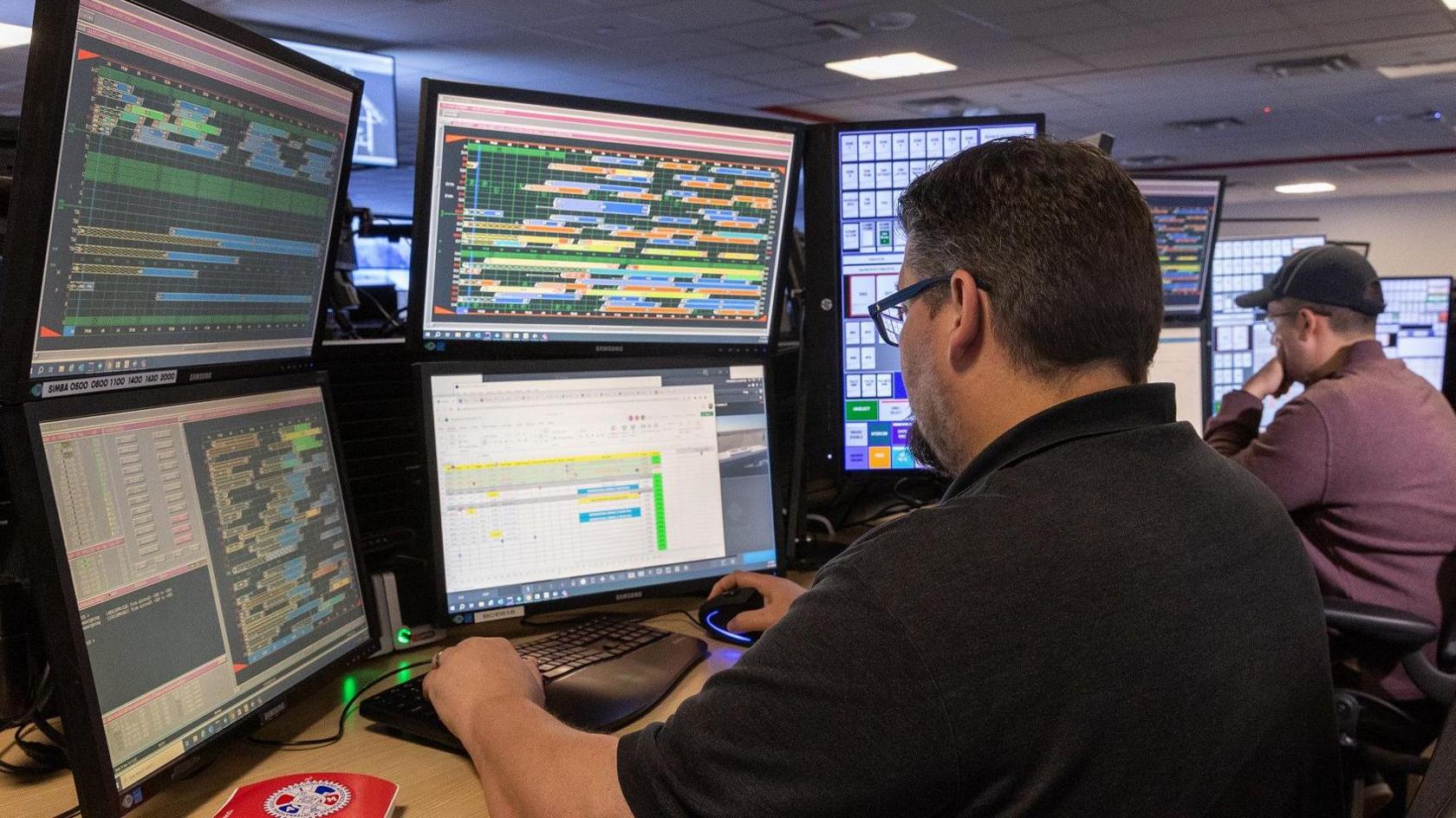 A worker at Dallas Fort Worth International Airport watches multiple screens used to direct operations.