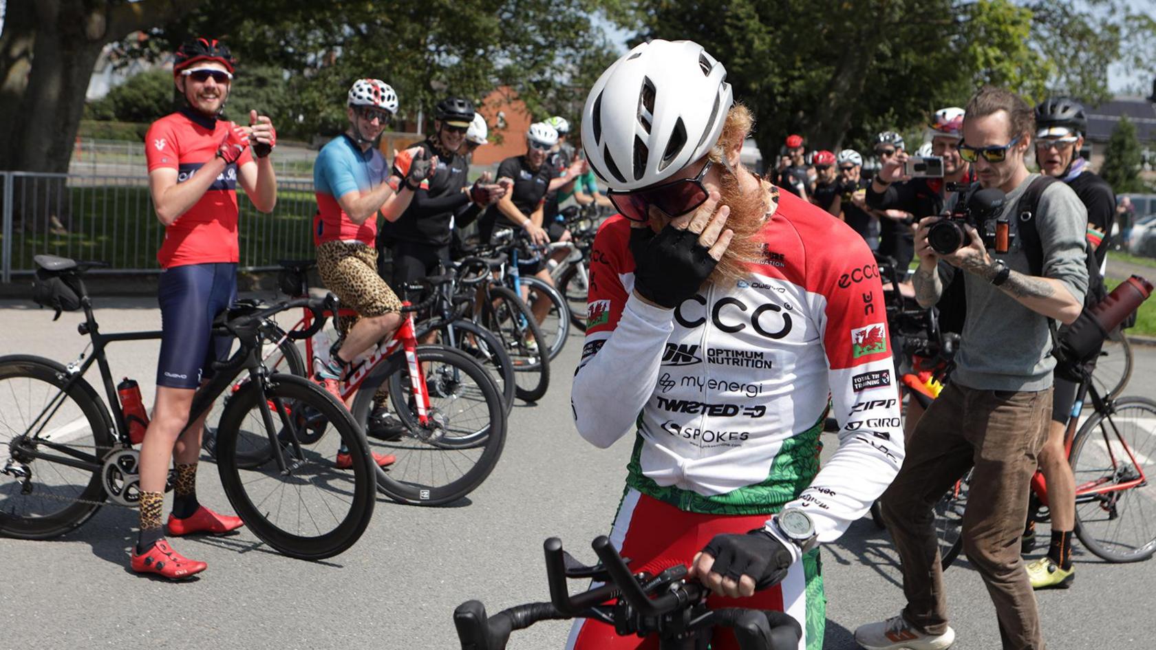 Sean with his face in his hands, other cyclists behind him