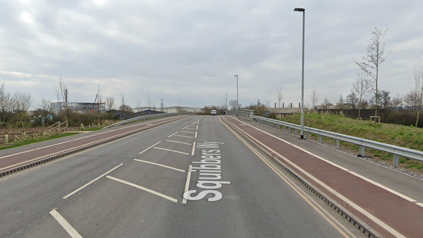 Squibbers way road in Bridgwater, where the road crosses the River Parrett. There is a white van in the background coming towards the camera and buildings on the left.