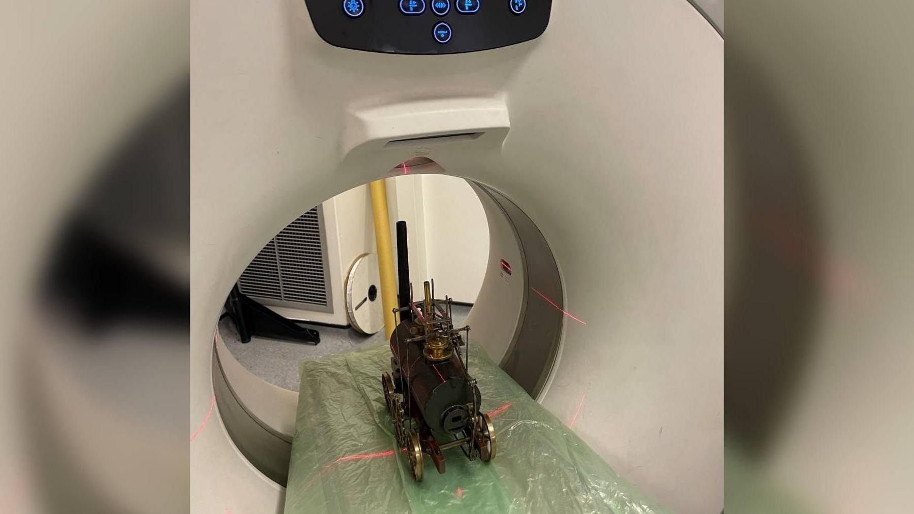 A model locomotive being put through a CT scanner.