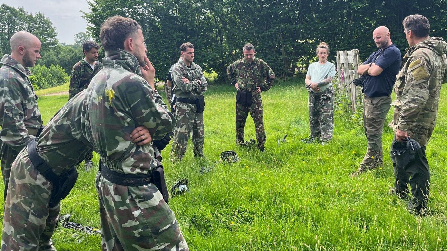 A group including Michael Bradley (left), Piet Cremers (fourth left) and Ella Masar (third right) listen to feedback after a military training exercise as part of the FAW's Uefa pro licence course