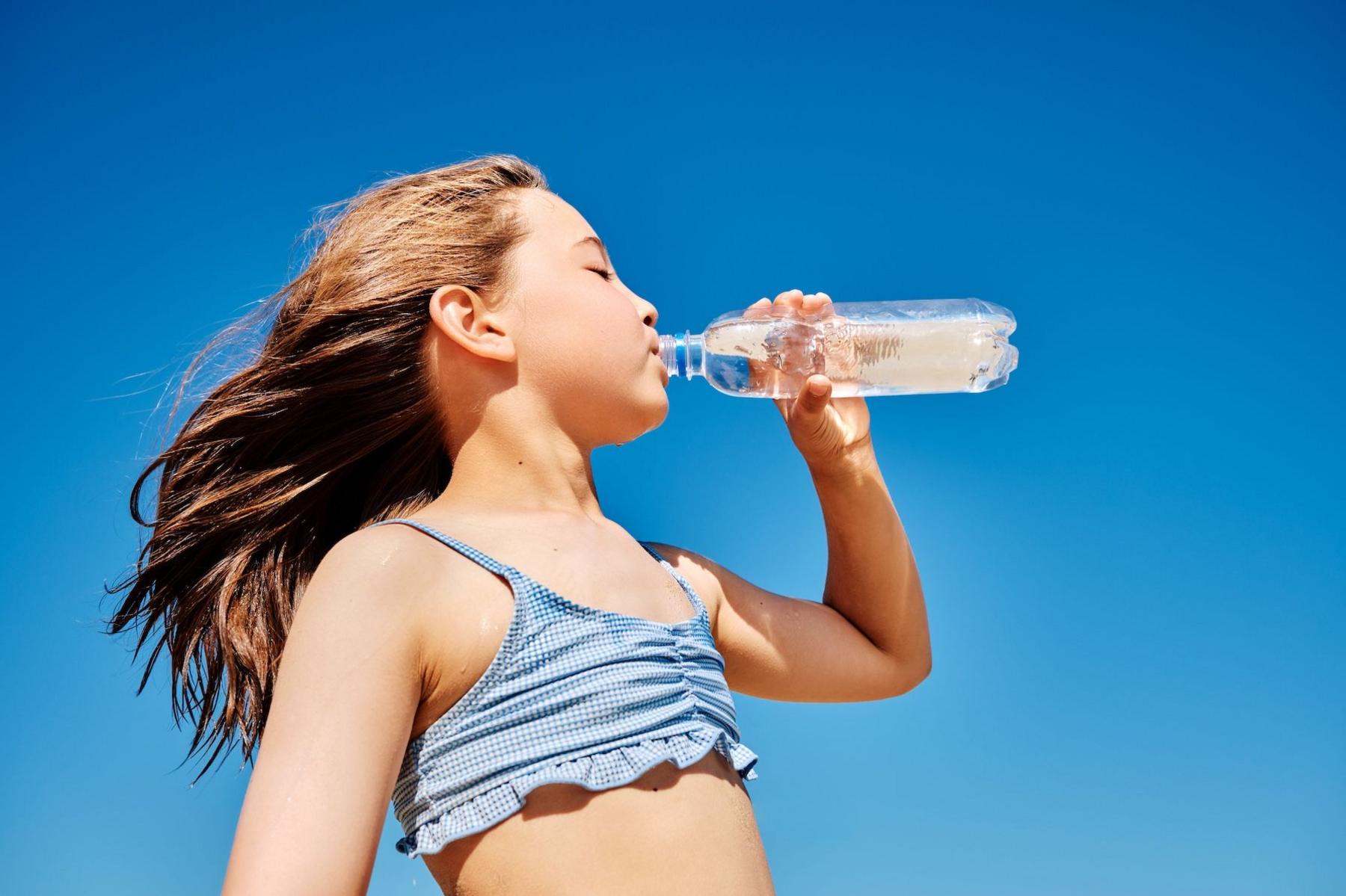 Girl in the sun drinking a bottle of water.