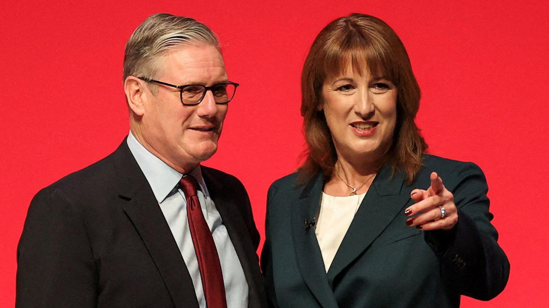 Prime Minister Sir Keir Starmer stands alongside his chancellor Rachel Reeves at Labour's annual party conference in September, in front of a red backdrop.