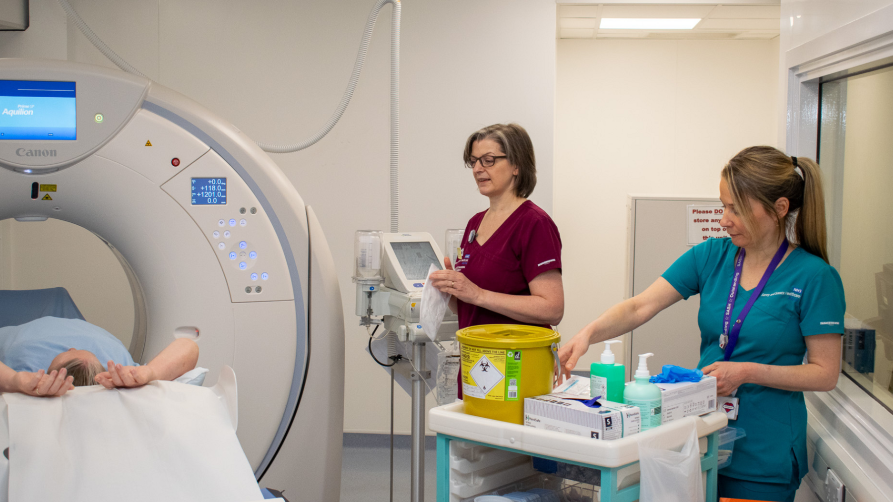 NHS staff operating a diagnostic machine wearing clinical scrubs