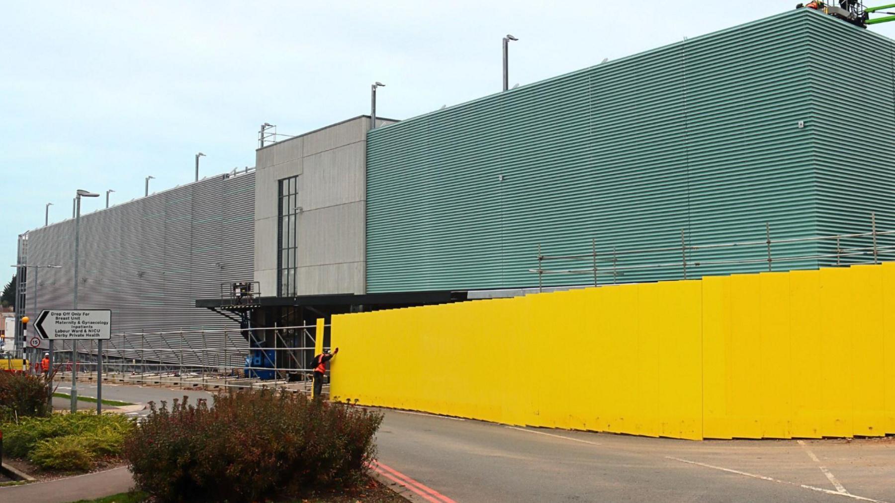 A nearly-finished car park behind bright yellow hoardings