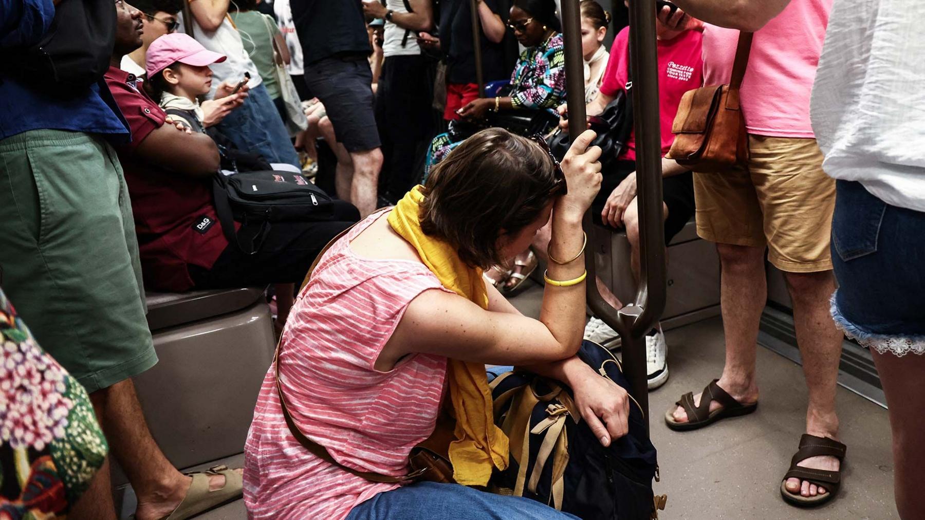 A woman sits on the floor of a crowded carriage on metro line 11 during a heatwave in Paris