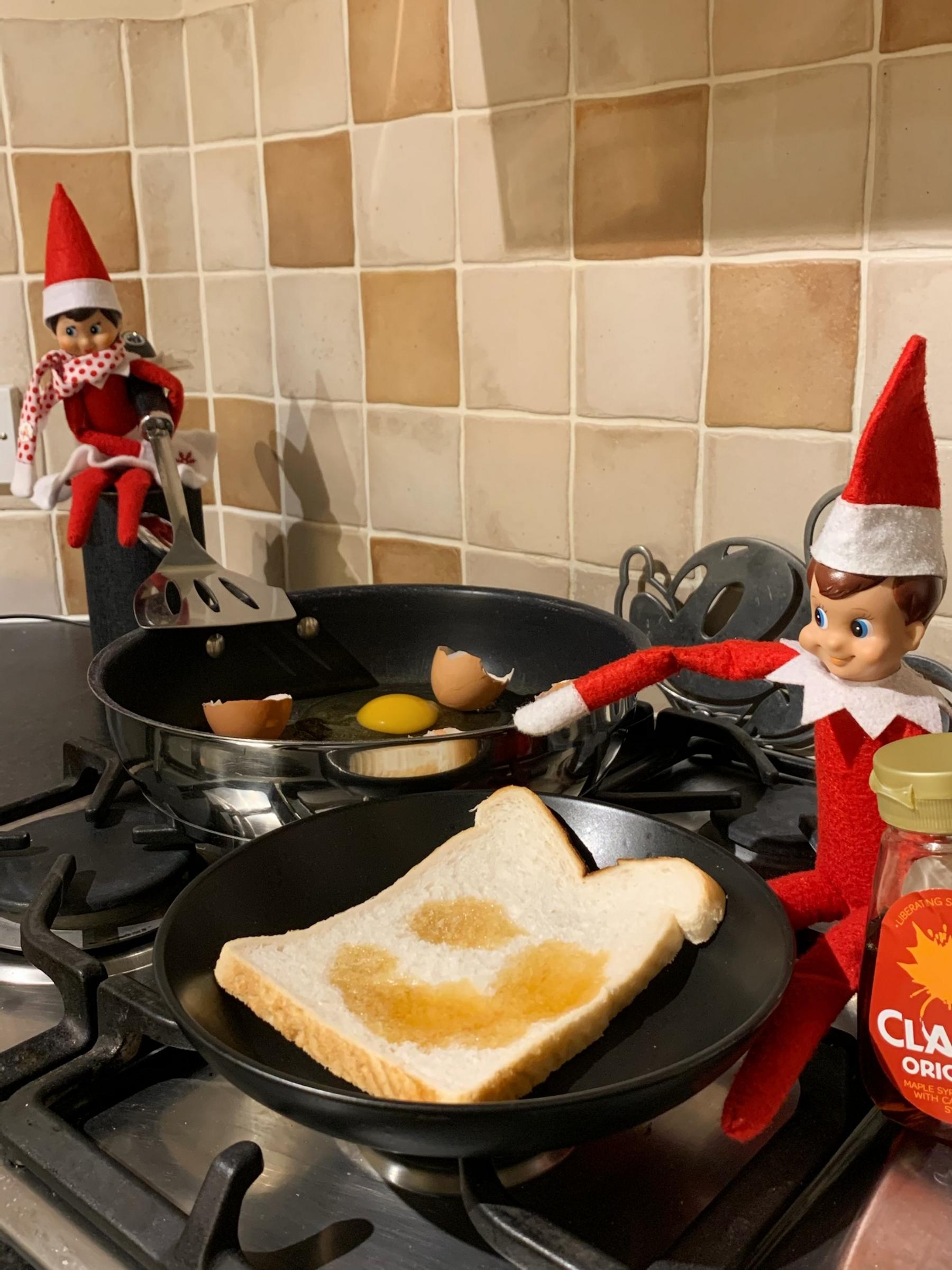 Two elves cooking eggs near pans in the kitchen