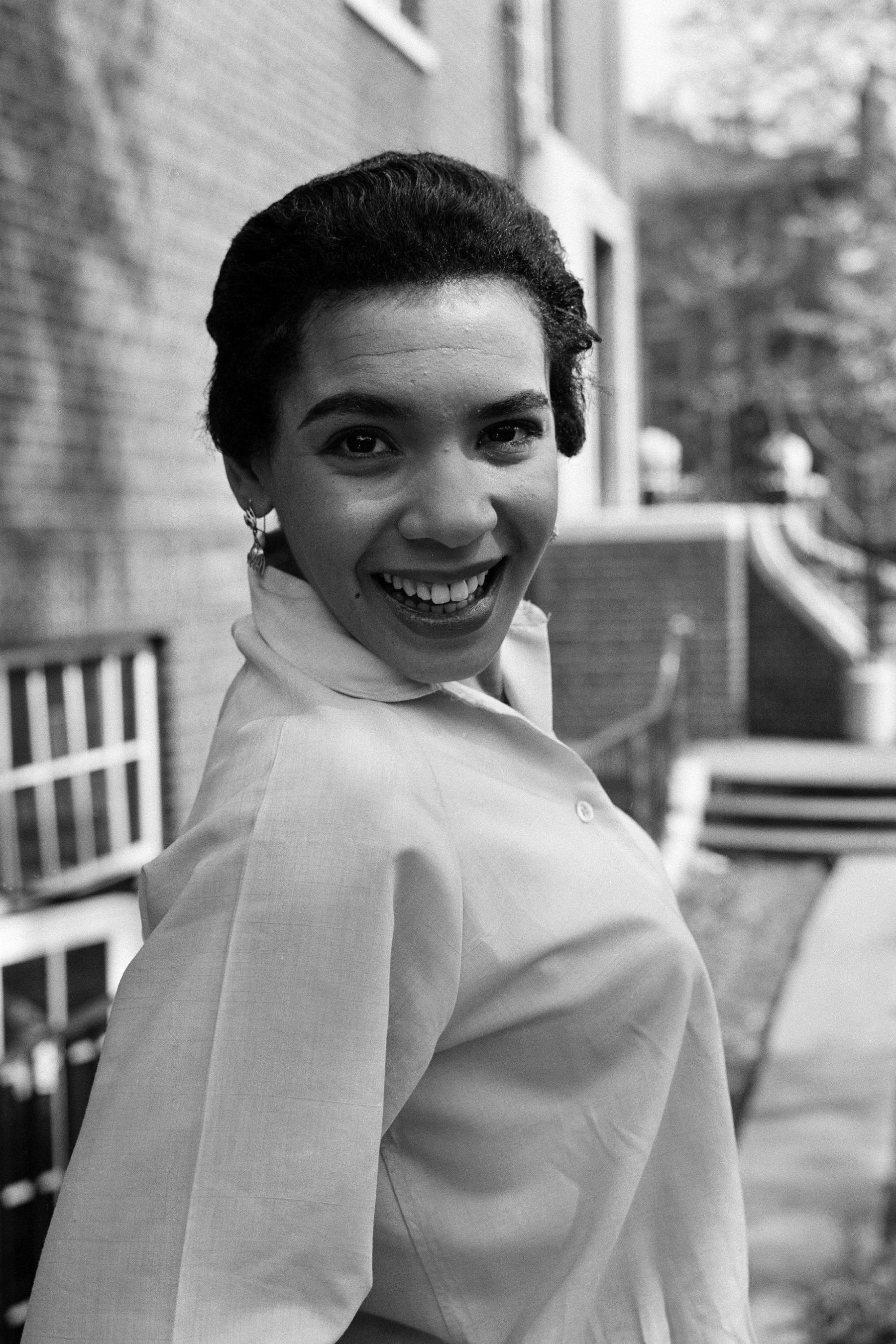 A black and white photo of young Shirley Bassey smiling and looking at the camera