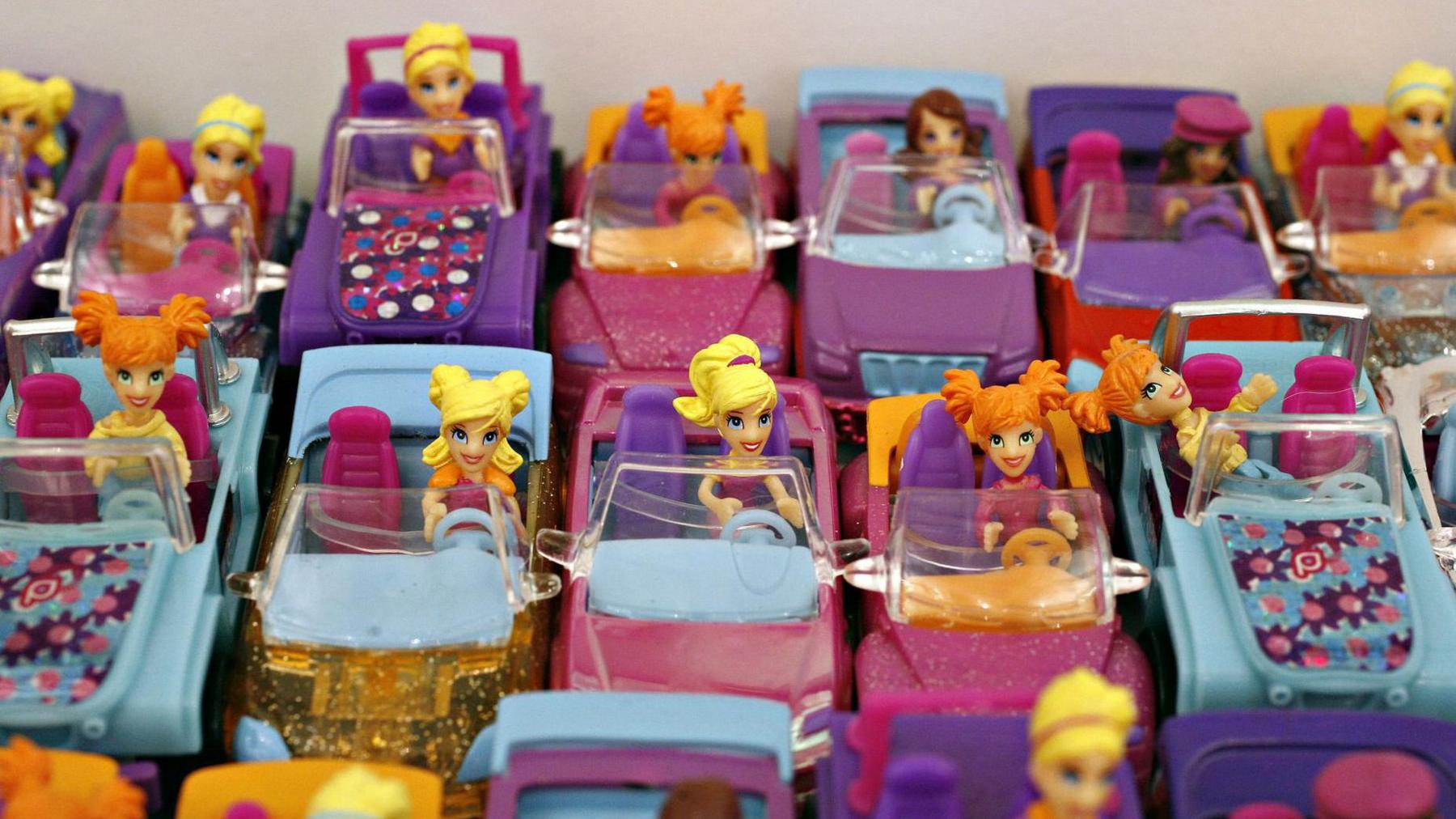 A row of Polly Pocket dolls, sat in cars 