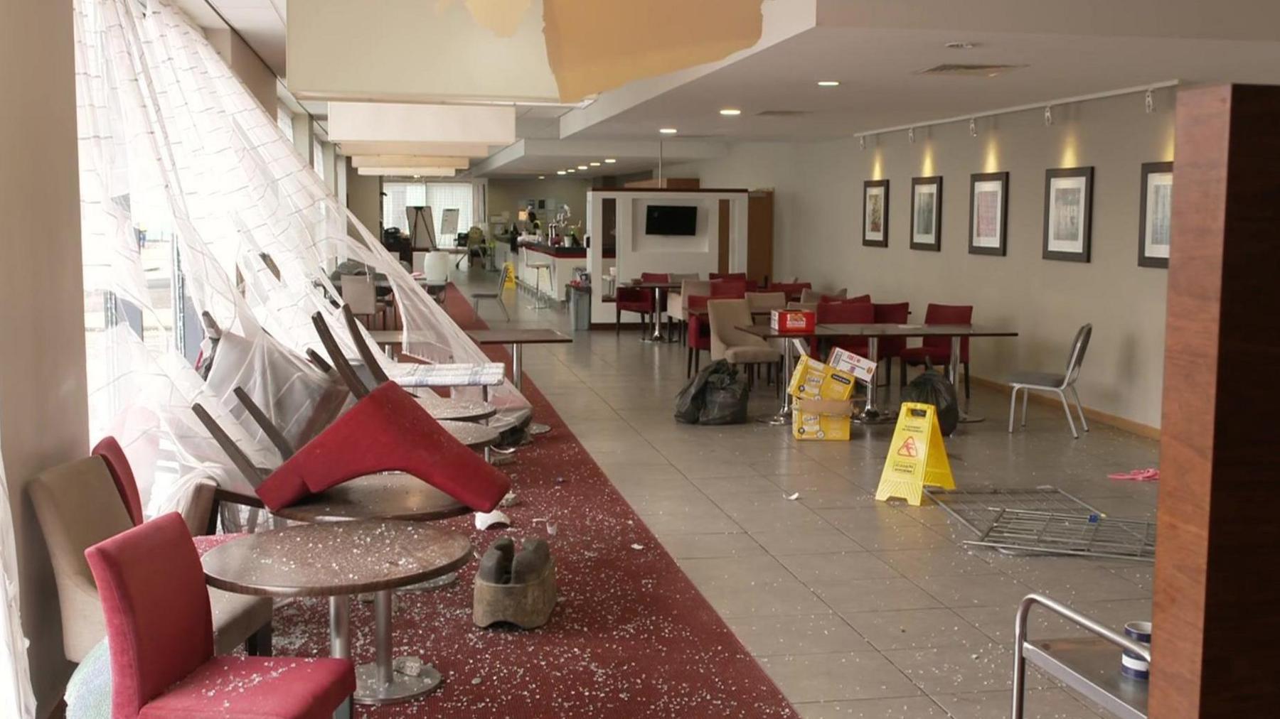 A picture showing damage inside the hotel which shows smashed glass across the floor with upturned chairs 