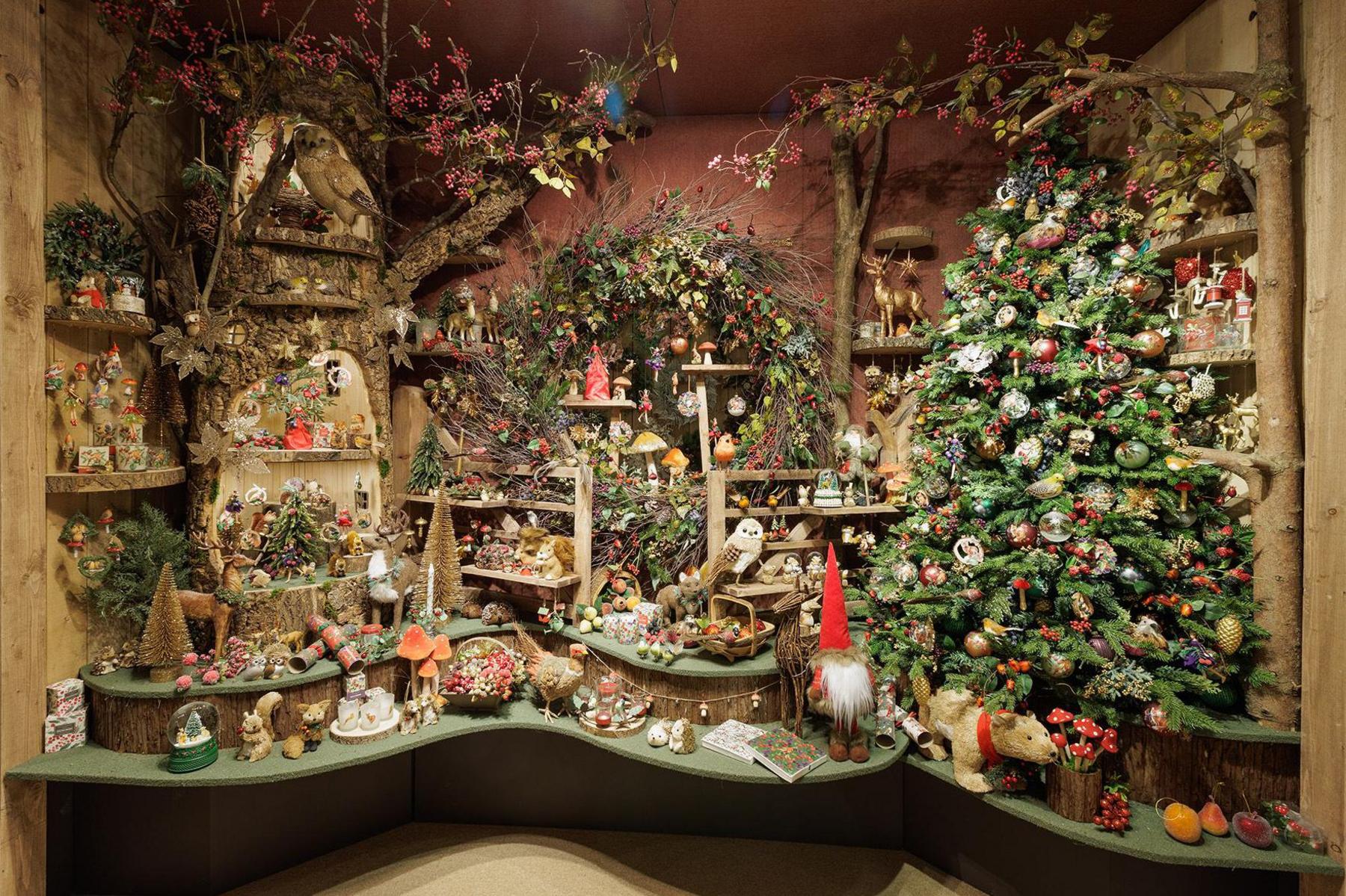 Display of Christmas decorations and wreaths with a tree trunk used to show them and a Christmas tree