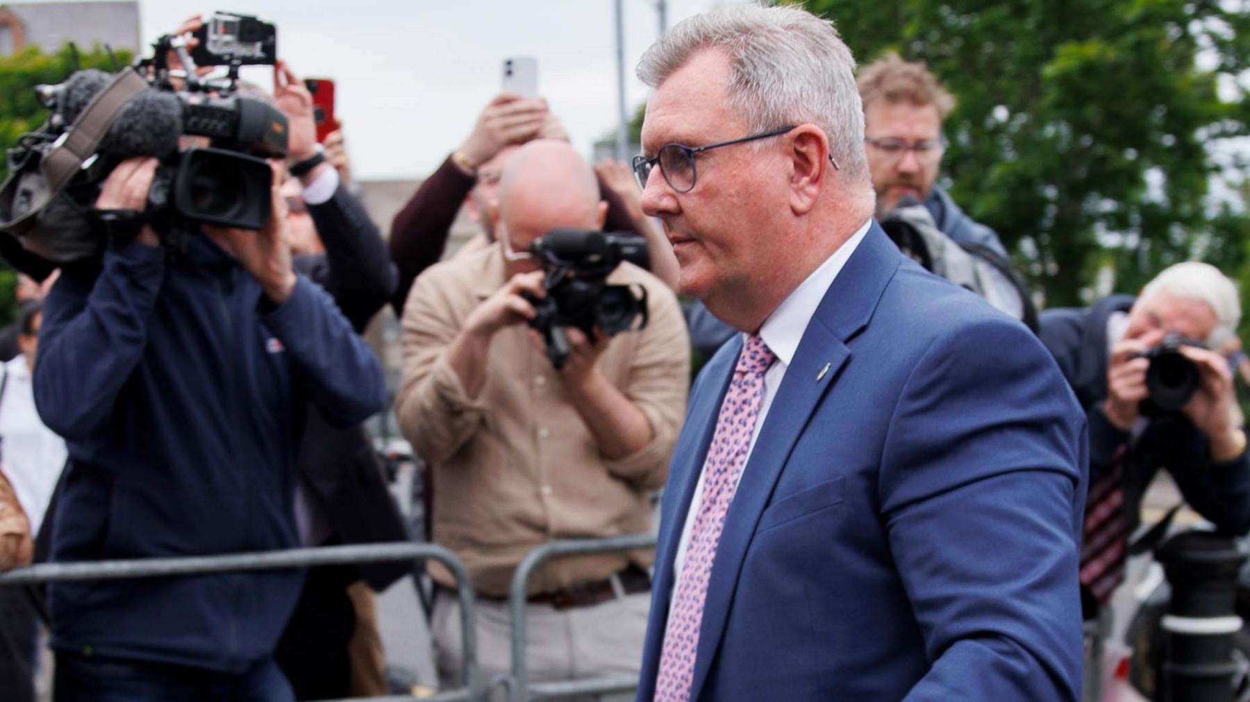 Sir Jeffrey Donaldson walks past a bank of photographers outside court wearing a blue suit
