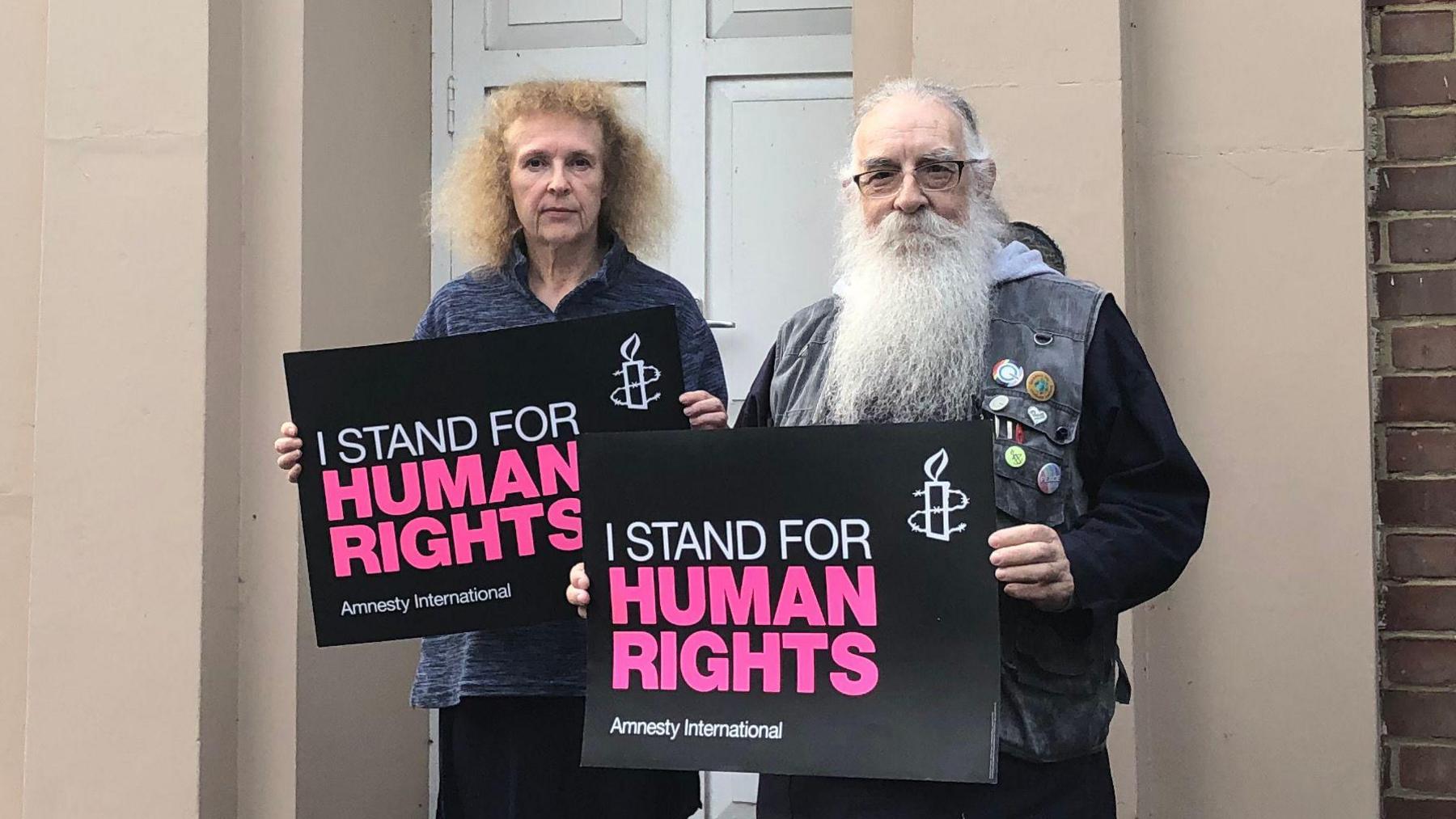 Jenny Brabazon and Mike Medhurst stand holding placards which read 'I stand for human rights'