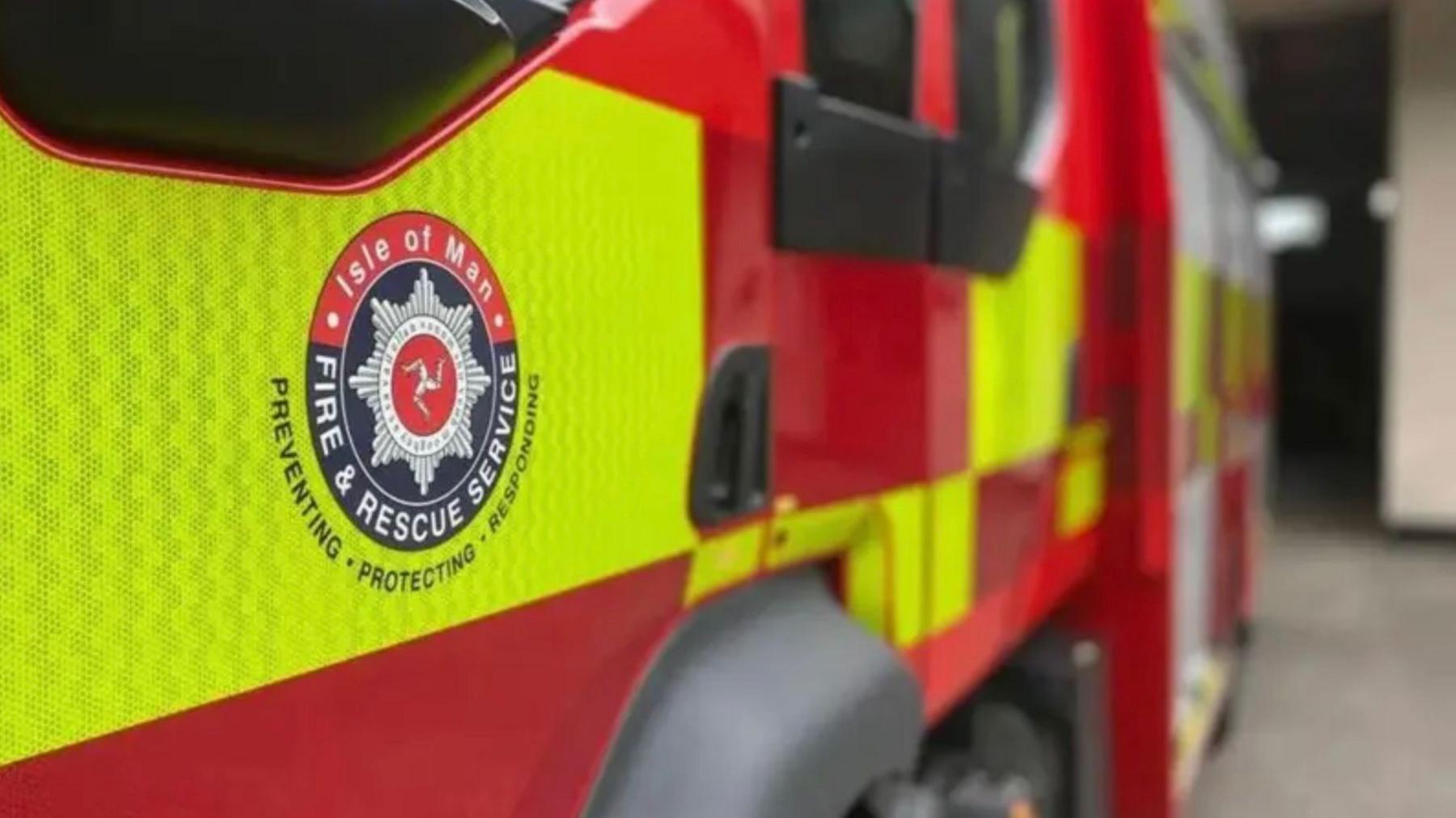 The Isle of Man Fire and Rescue Service blue and white emblem on the door of a parked fire engine.
