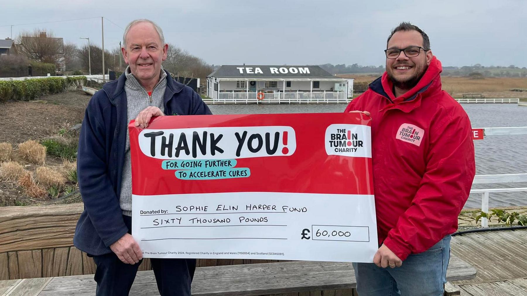 John Huggins holding a cheque for £60,000 alongside a man from the Brain Tumour Charity