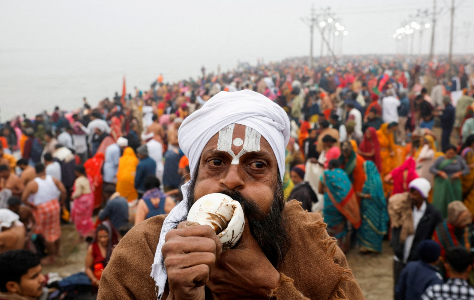 A Sadhu or a Hindu holy man blows a conch as he prays on the day devotees take a holy dip.