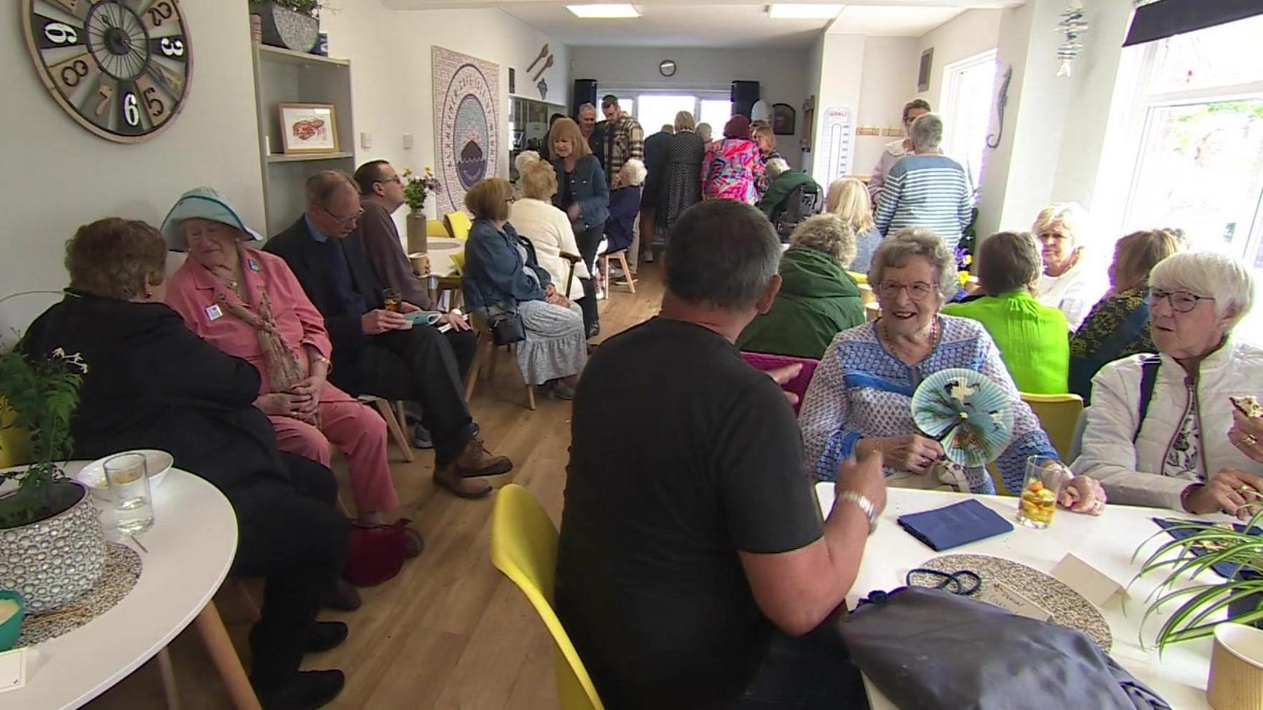 A cafe with older people sitting at tables and talking to each other