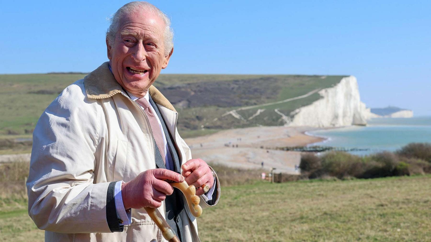 King Charles III stands in front of cliffs as he walks the King Charles III England Coast Path at Seven Sisters National Nature Reserve.