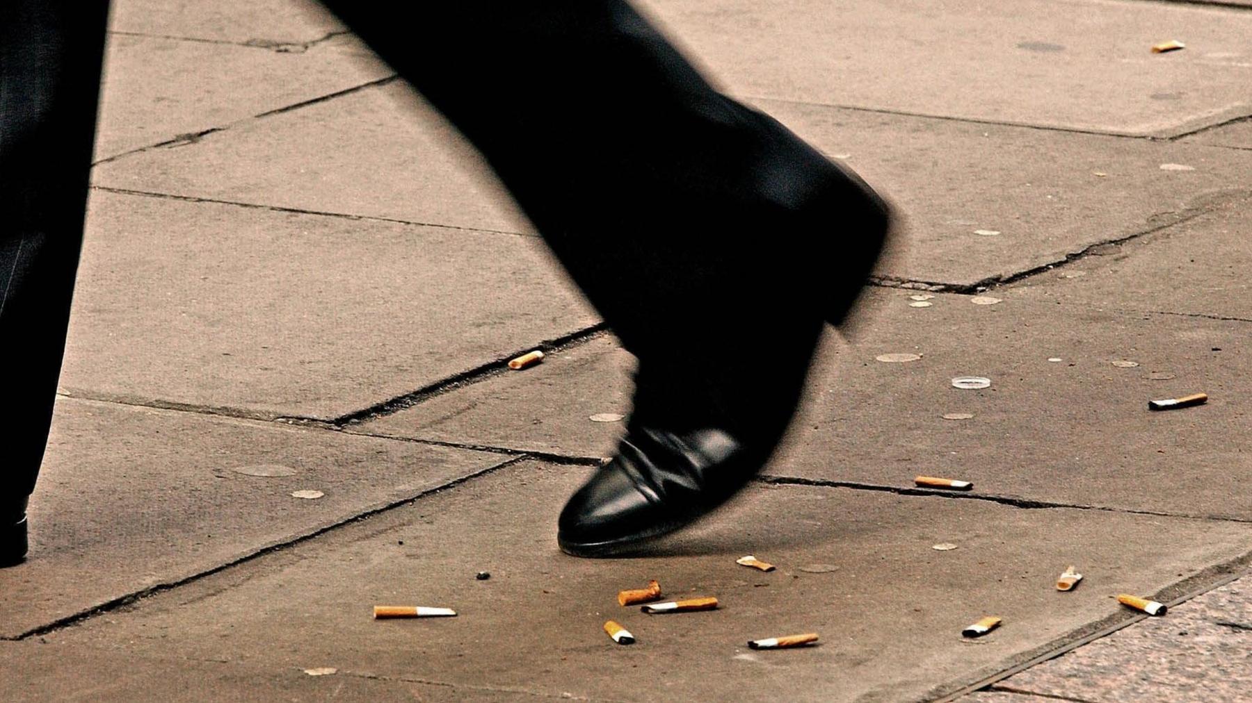 A man walking over discarded cigarette butts