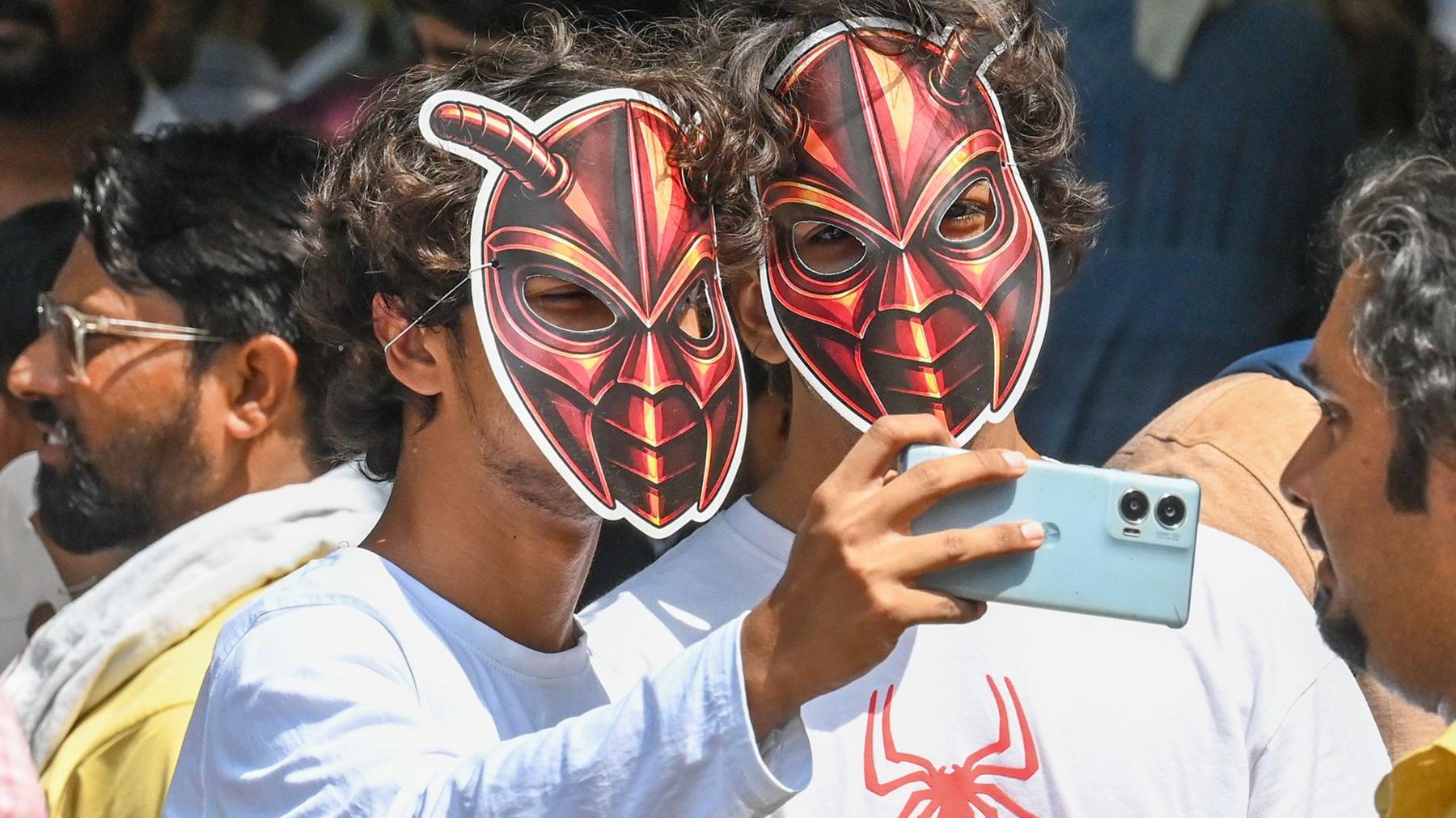 Two young male supporters of India's Cockroach Janta Party wearing cockroach masks and taking selfies during the cockroach protests in June 2026