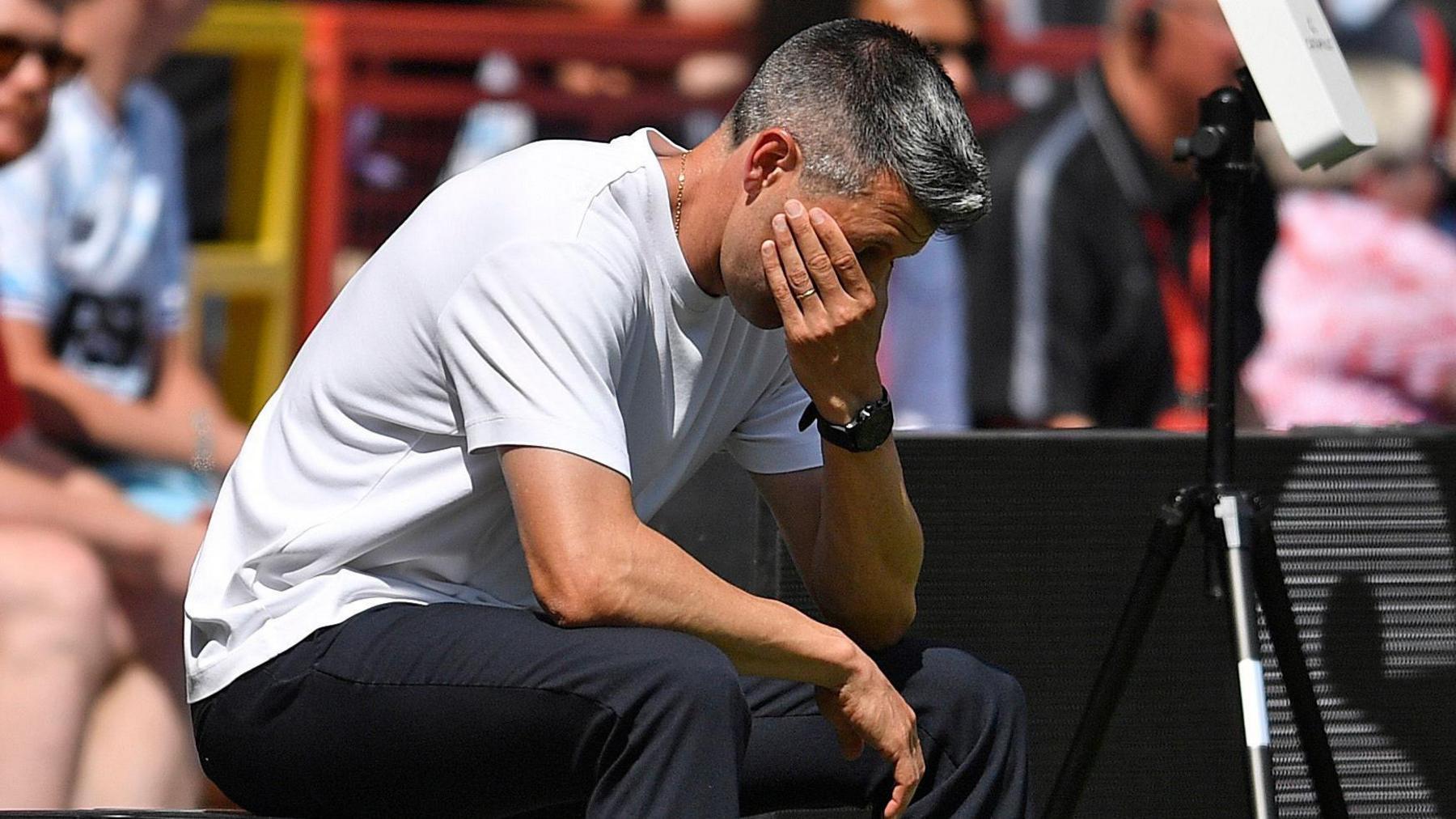 Watford boss Paulo Pezzolano with his hand over his eyes while sitting on the touchline