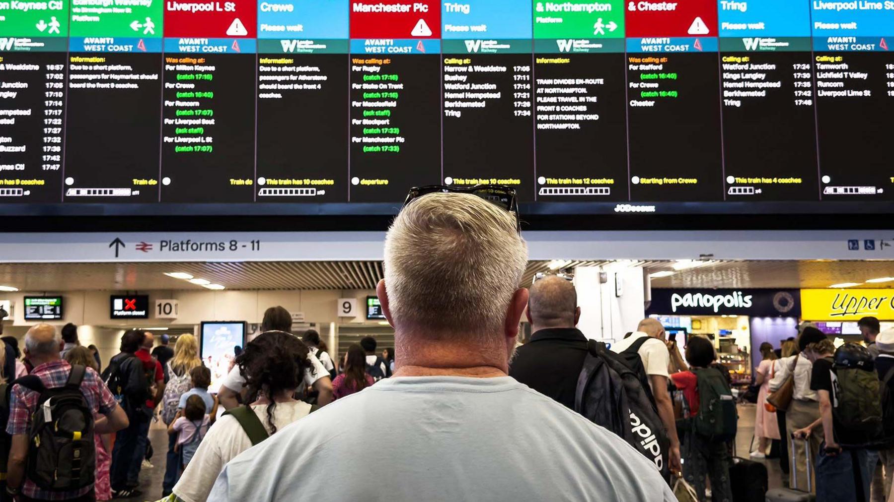 A man looking at the departure board at London Euston railway station