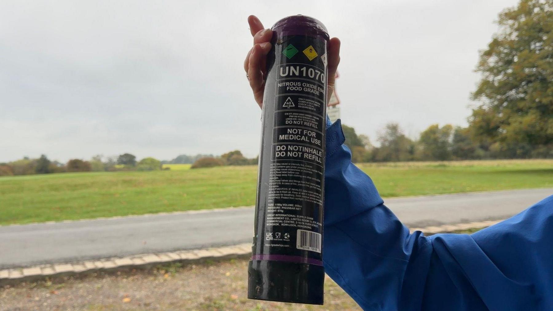 One of the canisters found at Beverley Westwood, It is black and has multiple warning signs on the canister. The canister is about the size of the forearm of the lady who is holding it. 