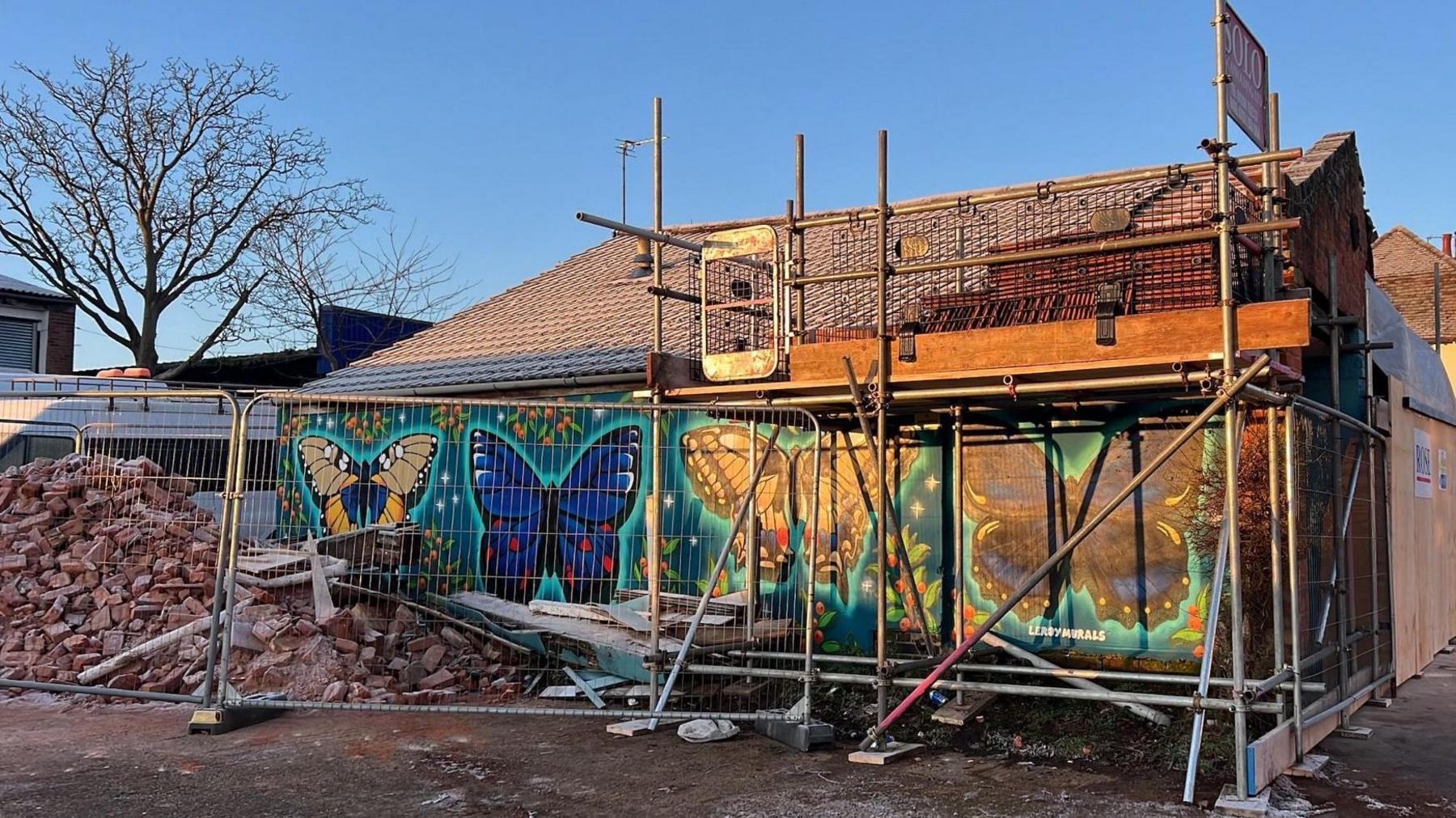 Scaffolding and rubble behind fencing at the damaged buidling