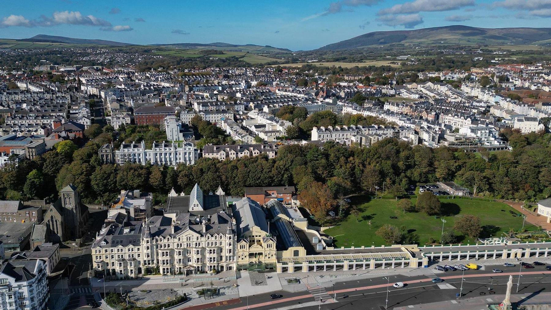 Douglas promenade and inland rooftops from the air on a sunny day with the rolling green hills in the background.