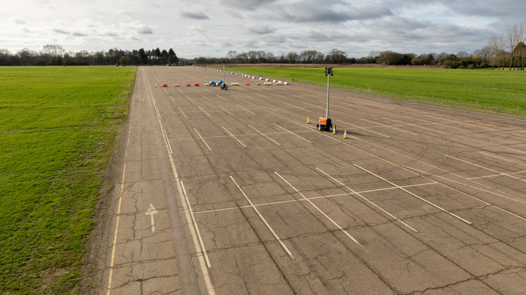 An empty runway at Bovingdon Airfield which is part of the studio. Some lighting and safety equipment has been set up on the runway.