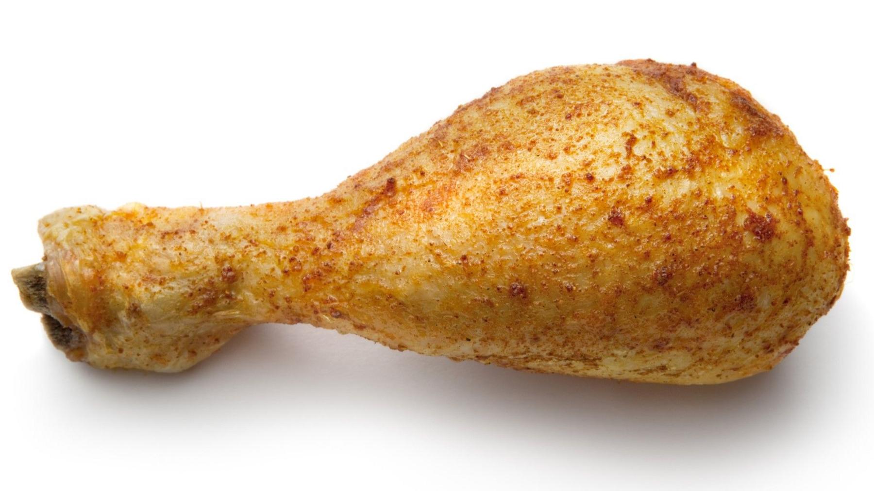 A golden-coloured cooked chicken drumstick set against a white background.