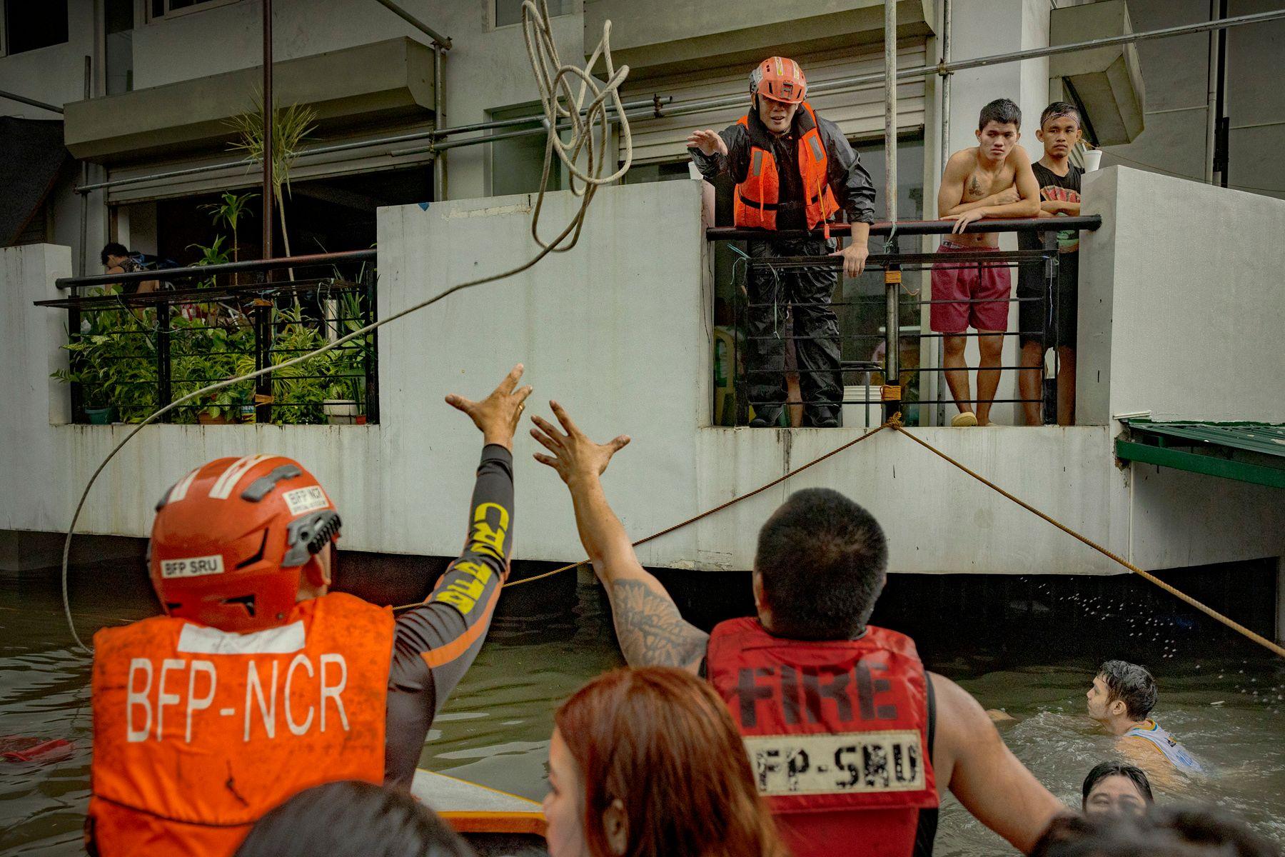 Rescuers reach for a rope as they ride a boat to reach residents trapped by flooding caused by Typhoon Gaemi and monsoon rains on July 24, 2024 in Quezon city, Metro Manila, Philippines.