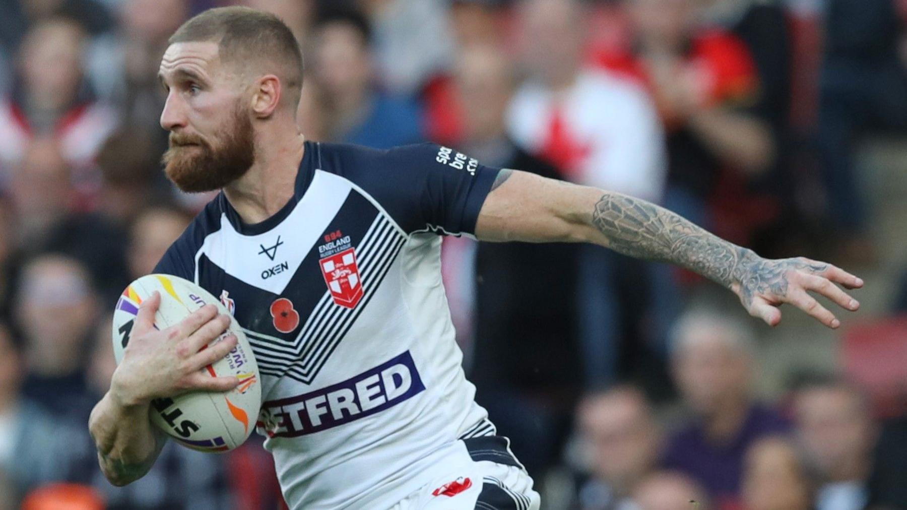 Sam Tomkins, wearing an England shirt, runs with the ball