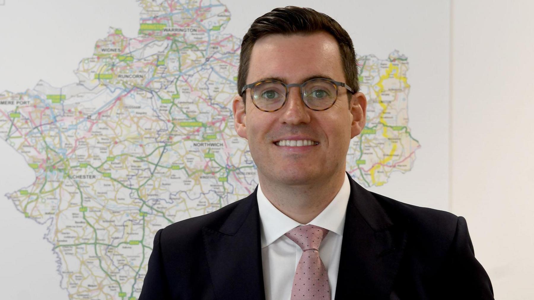 Cheshire Police and Crime Commissioner Dan Price in front of a map of Cheshire