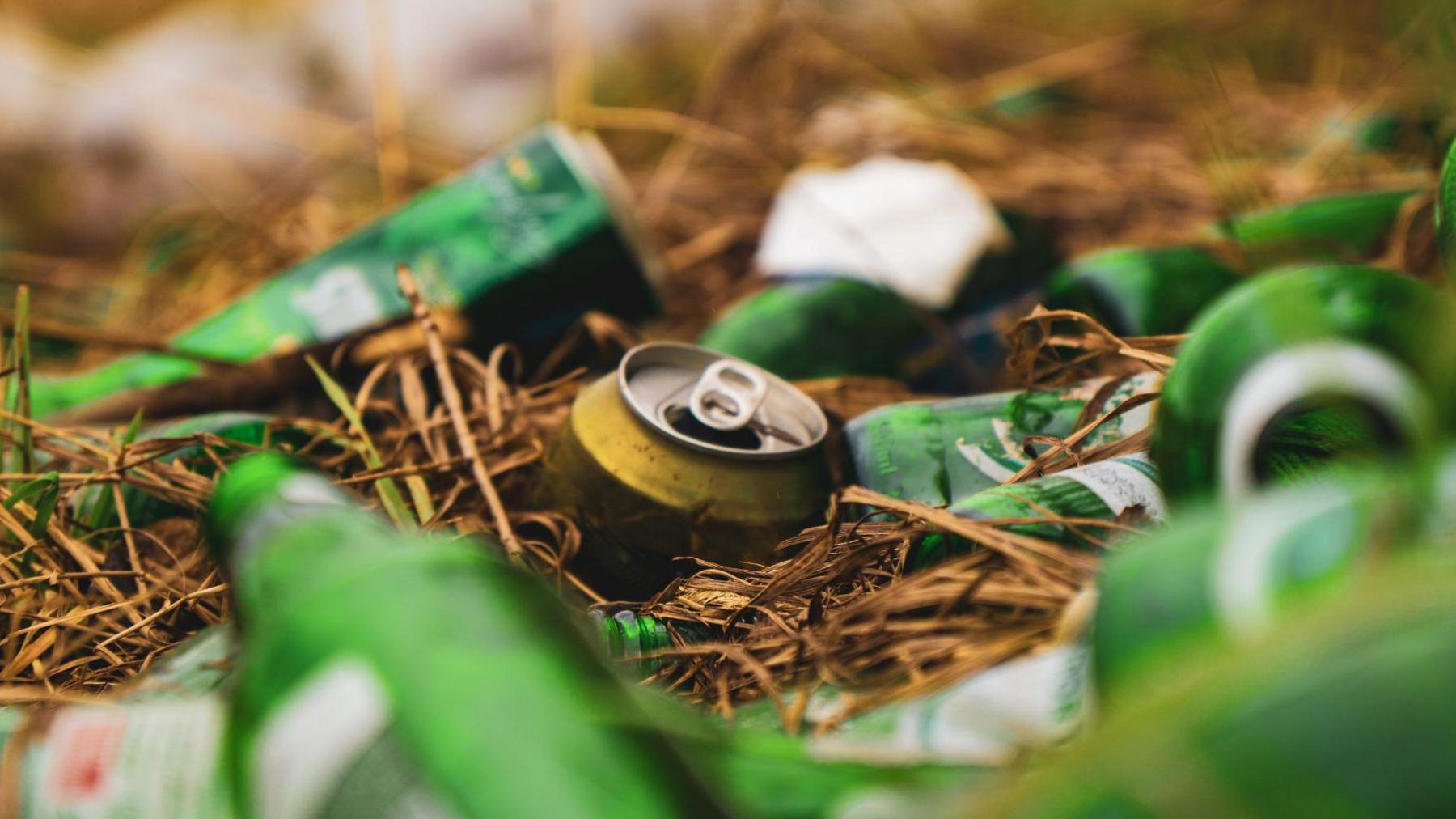 A pile of discarded green beer bottles lying scattered on the ground, reflecting light and creating a mess in the environment.