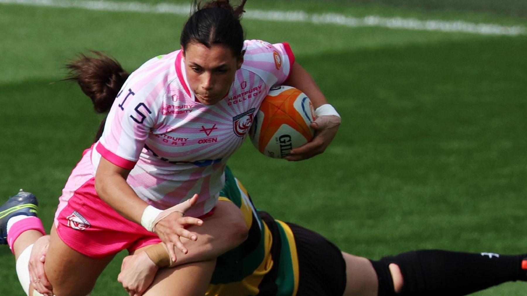 Pip Hendy of Gloucester-Hartpury is tackled by Emily Scarratt of Loughborough Lightning