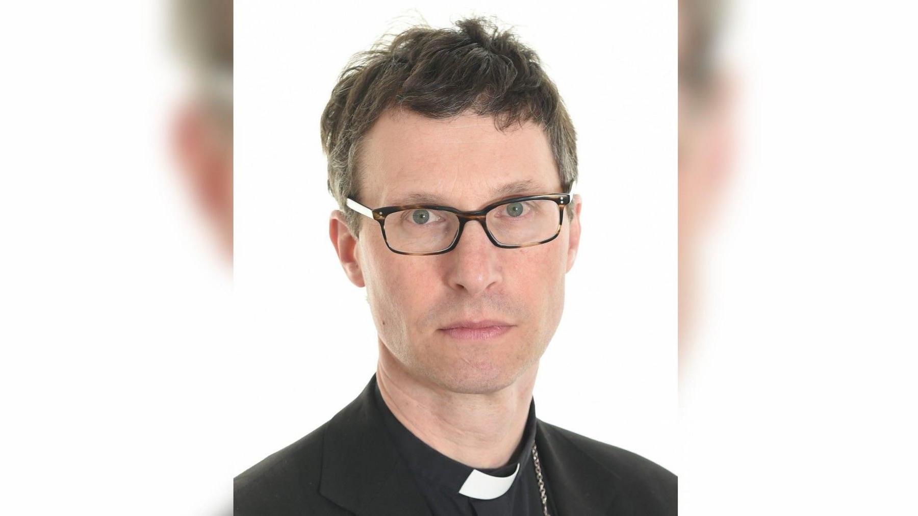 Portrait picture of Bishop of Blackburn Philip North. He is wearing glasses and a black suit with white collar