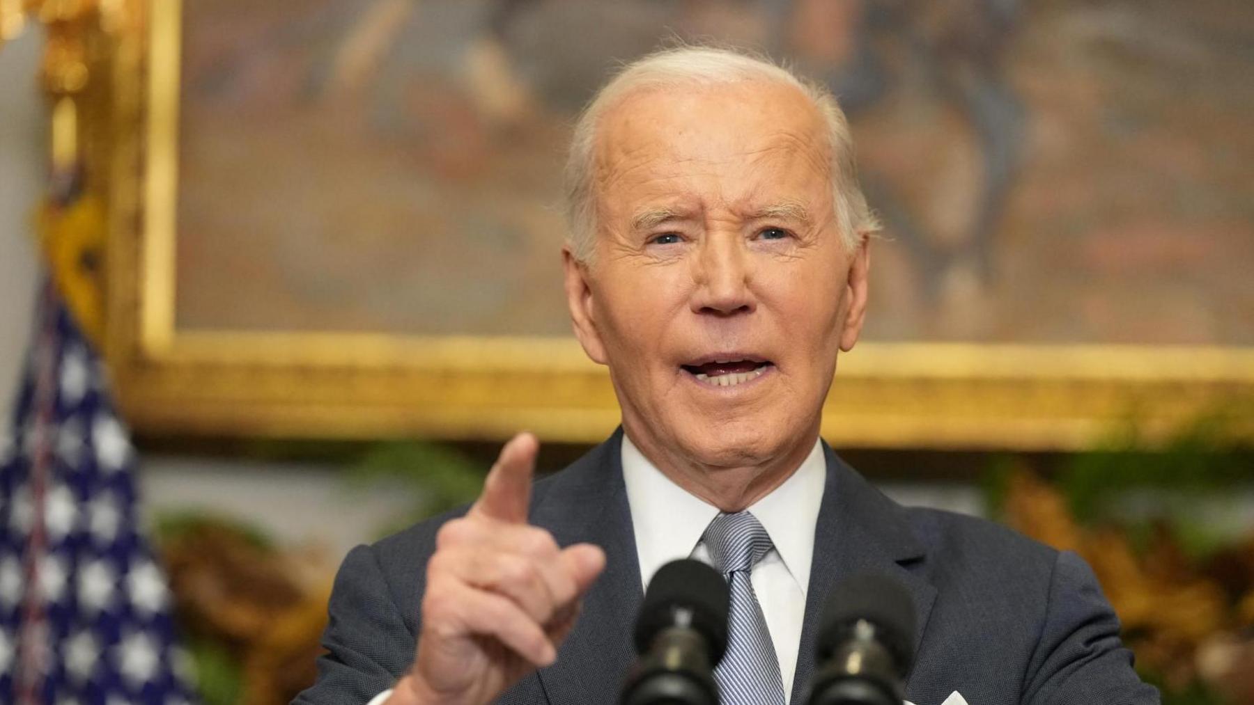 President Biden speaks to reporters from a podium inside the White House after the fall of Bashar al-Assad.