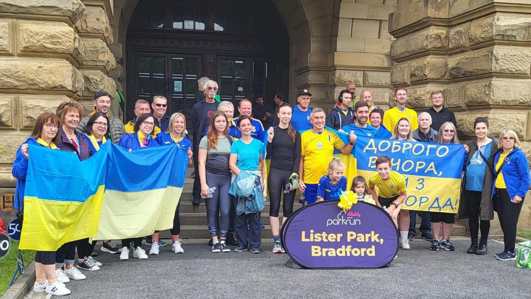 Runners standing on stone steps holding blue and yellow Ukrainian flags