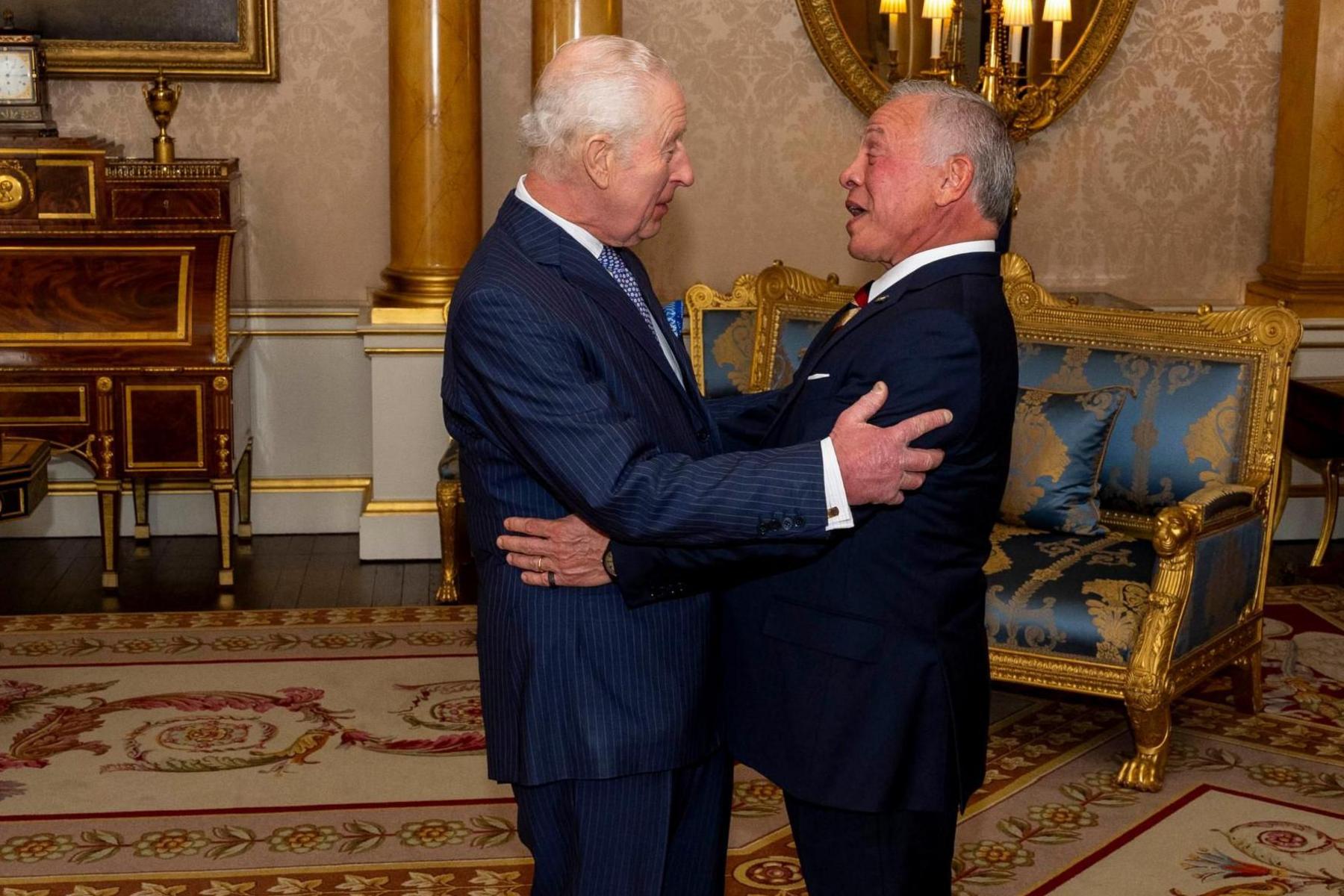 King Charles III greets Jordan's King Abdullah at Buckingham Palace. The two men are pictured face to face and they look pleased to see each other.