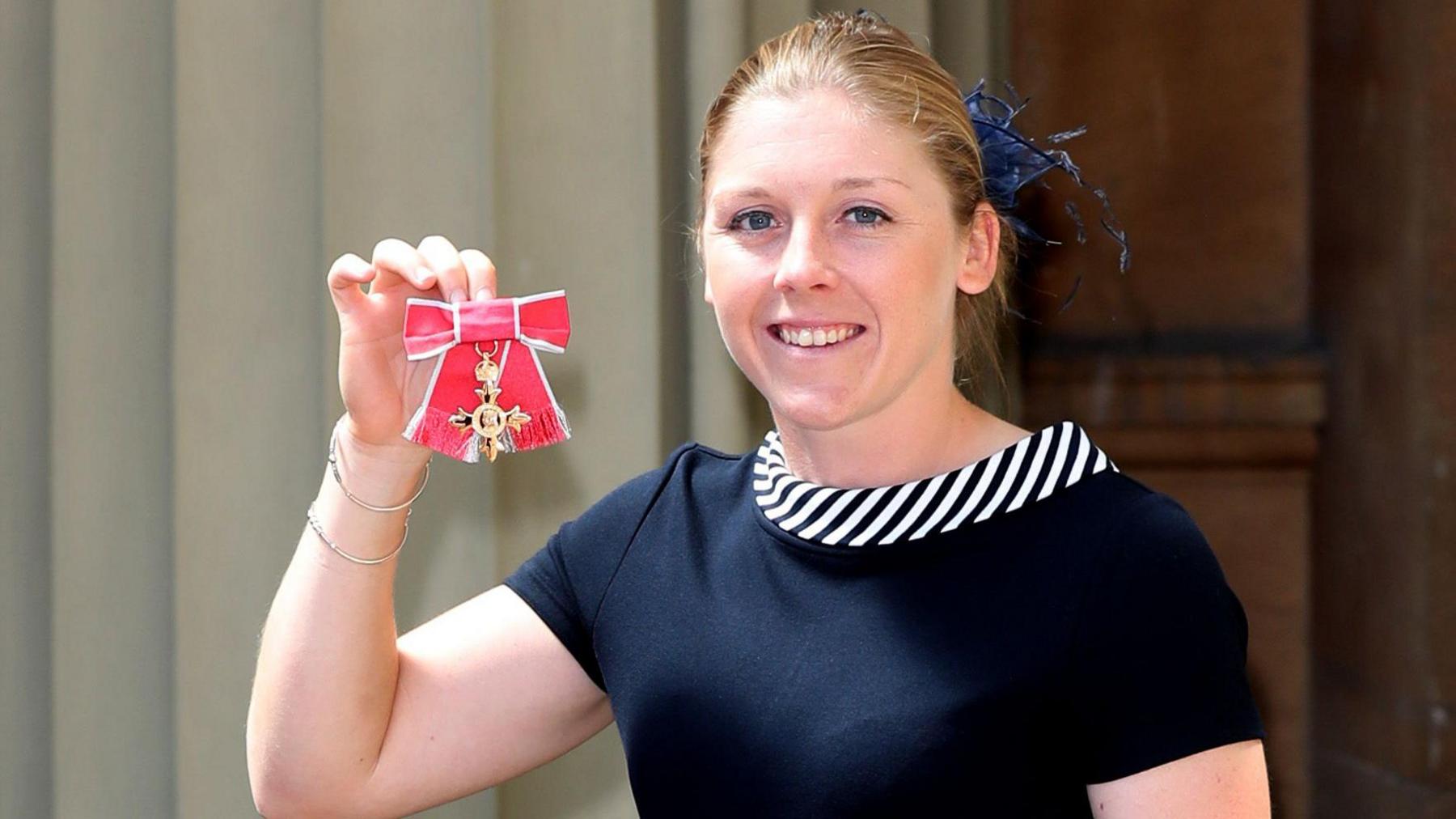 Heather Knight holding up her OBE medal