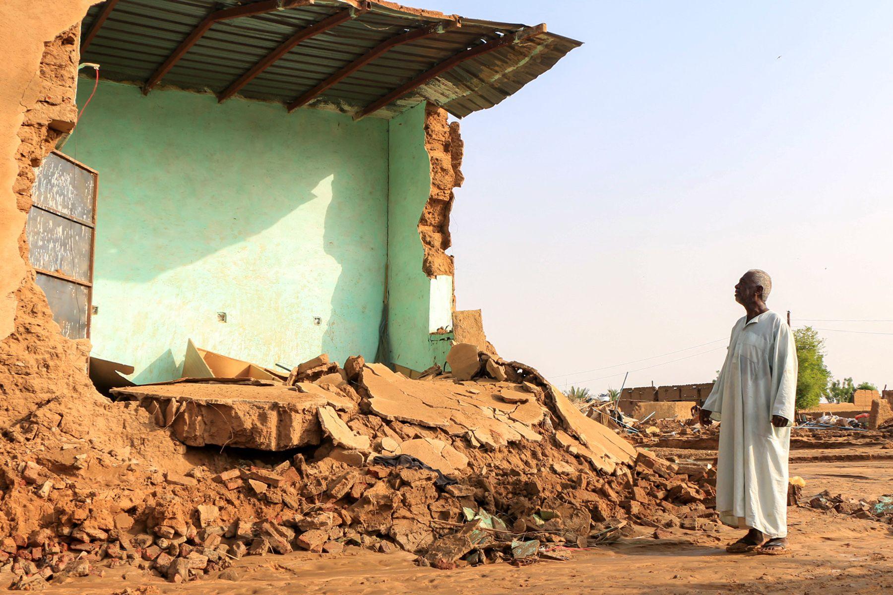 An elderly man stands before the collapsed mudbrick wall of a house in the aftermath of flooding in the area of Messawi near Meroe in Sudan's Northern State on August 28, 2024.